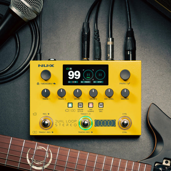 Yellow Nux guitar effects pedal with cables and a microphone on a dark surface